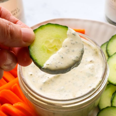 vegan ranch dressing lifted on a cucumber.