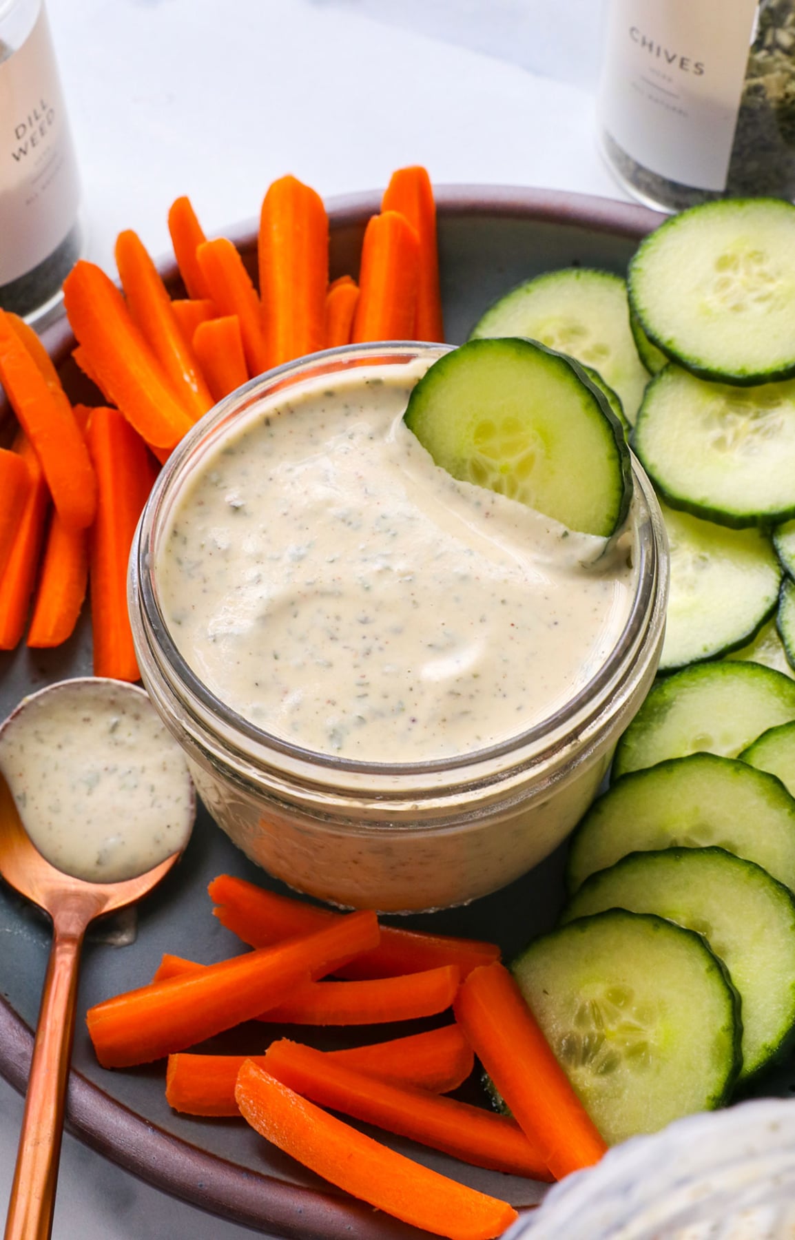 cup of ranch dressing served with sliced veggies for a dip.
