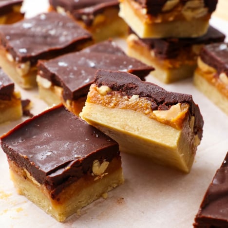 two healthy snickers bars cut on a parchment lined cutting board.