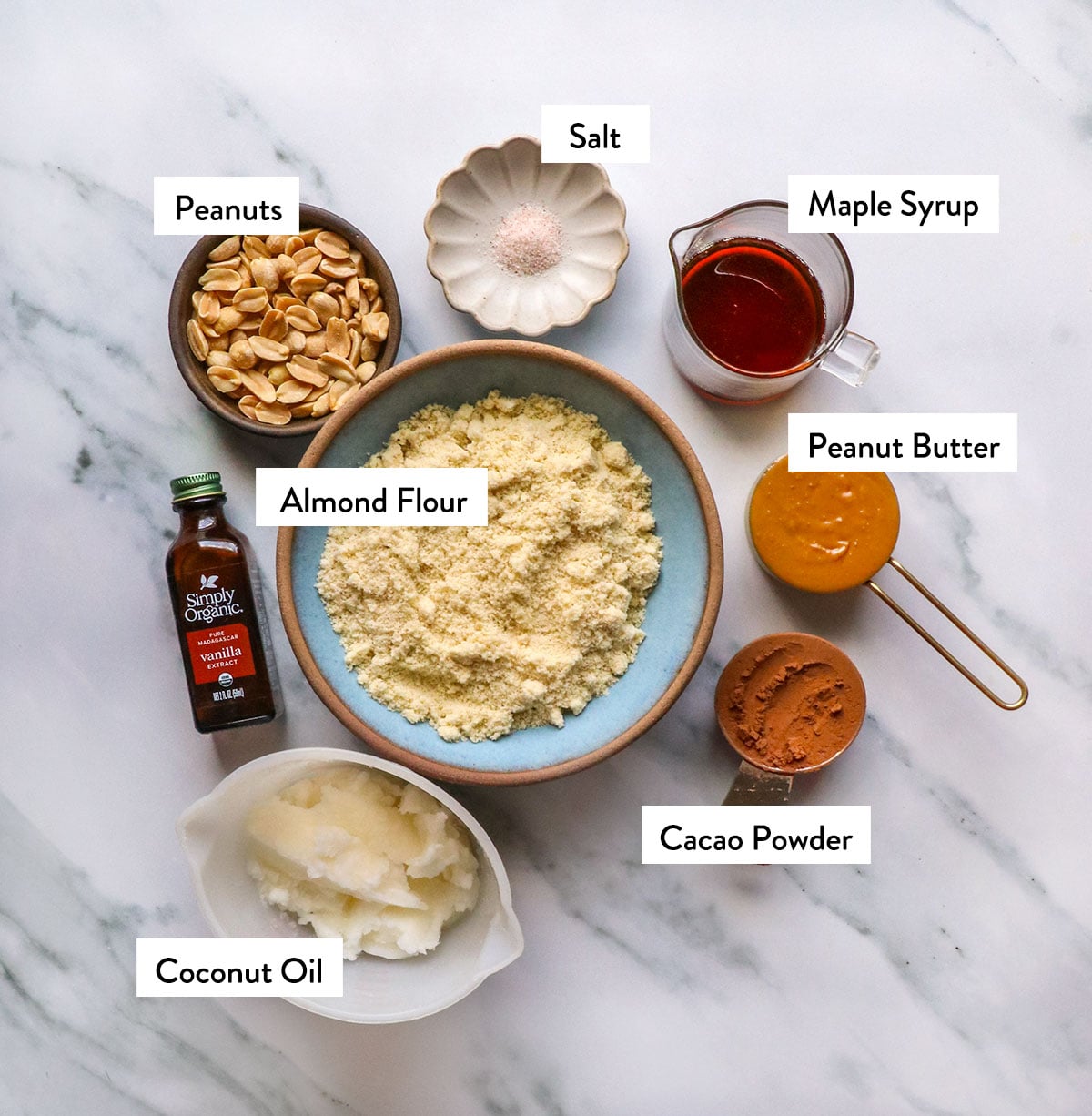 bowls of almond flour, maple syrup, peanut butter, cacao powder, coconut oil, and peanuts. 