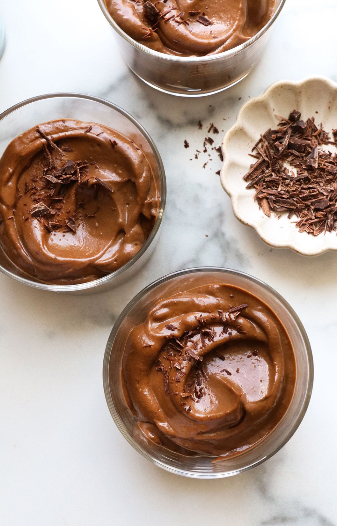 chocolate avocado pudding served in 3 glass jars.