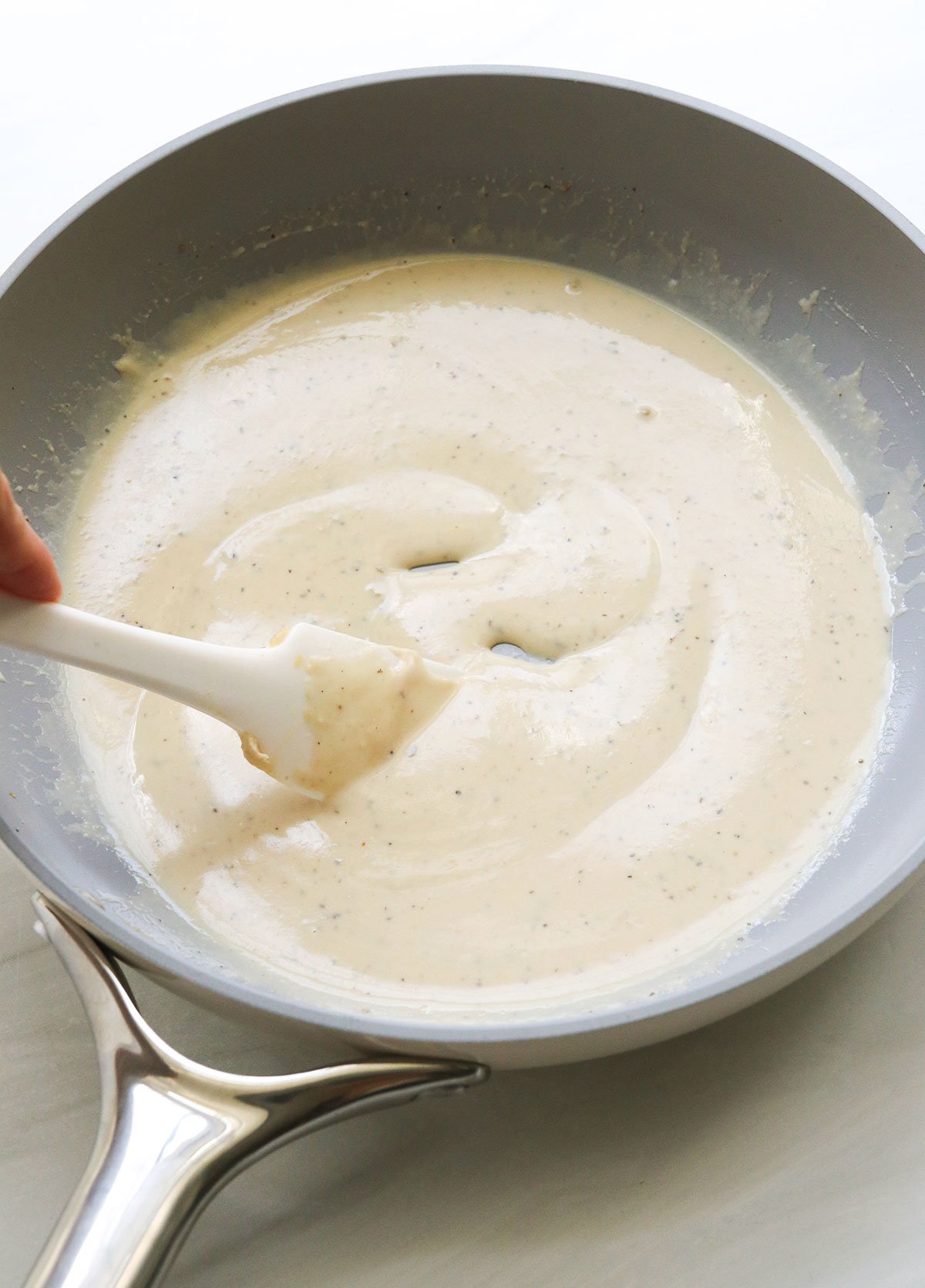 creamy hummus sauce in a gray skillet.