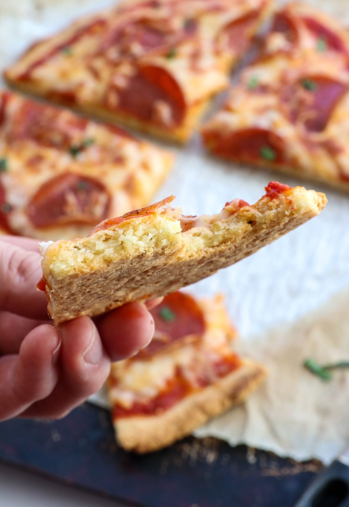slice of almond flour pizza lifted up to show texture.