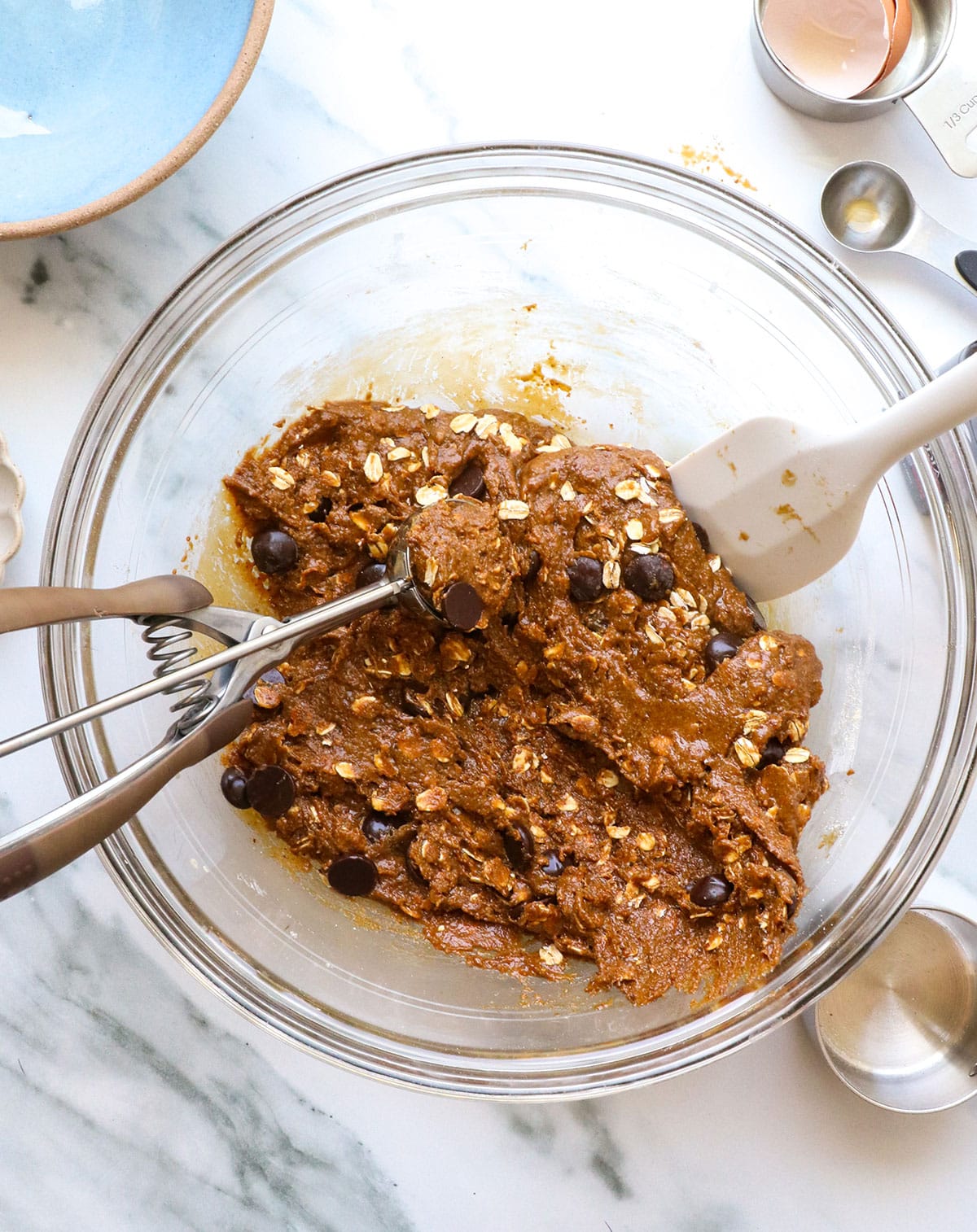 oats and chocolate chips folded into the dough with a scoop.