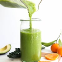 kale smoothie poured into a glass from the blender pitcher.