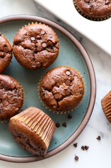 chocolate zucchini muffins on a blue plate with chocolate chips.