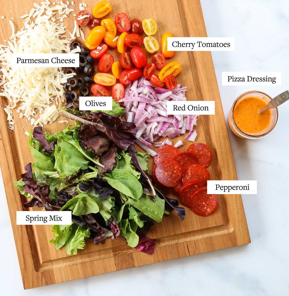 pizza salad ingredients labeled on a cutting board.