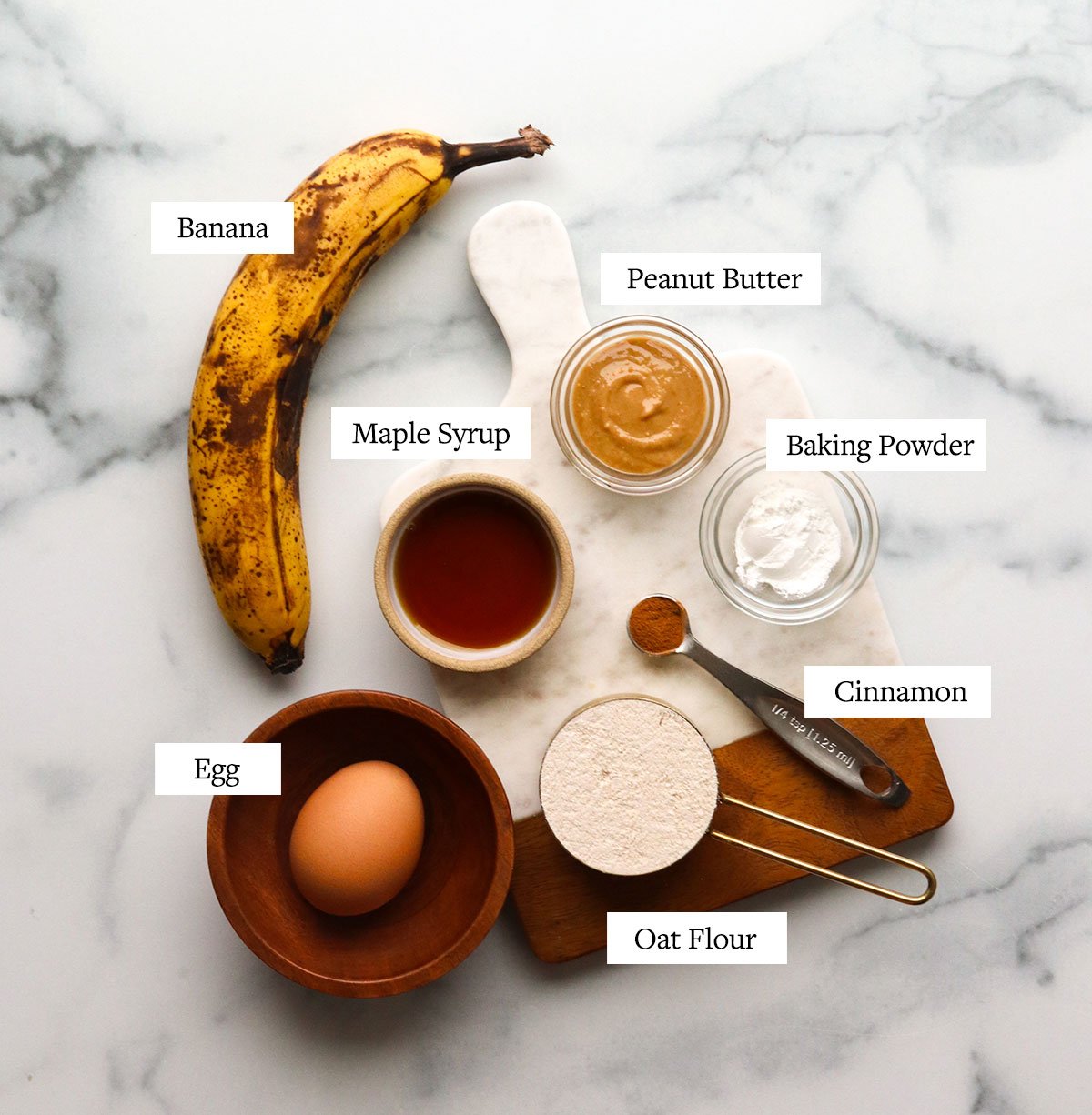 banana mug cake ingredients labeled on a marble cutting board.