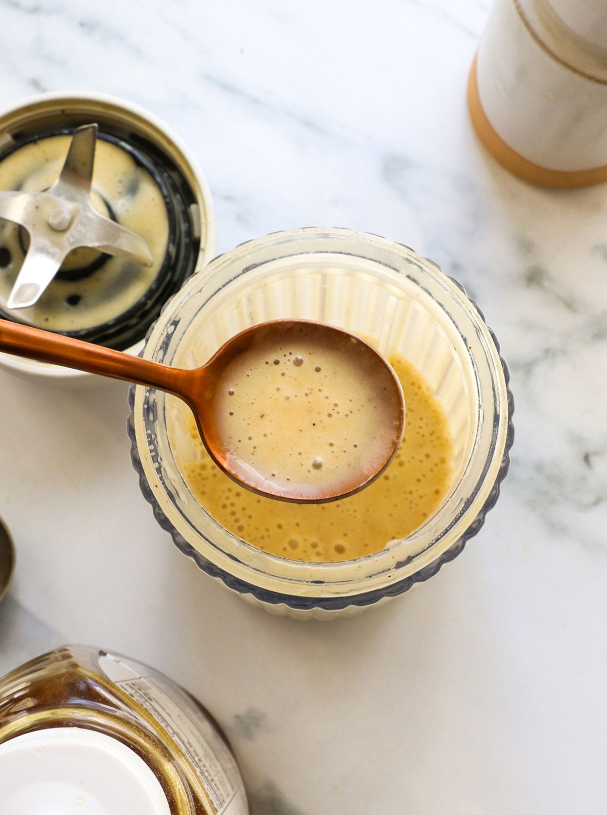 spoon lifting the champagne vinaigrette over a small blender. 