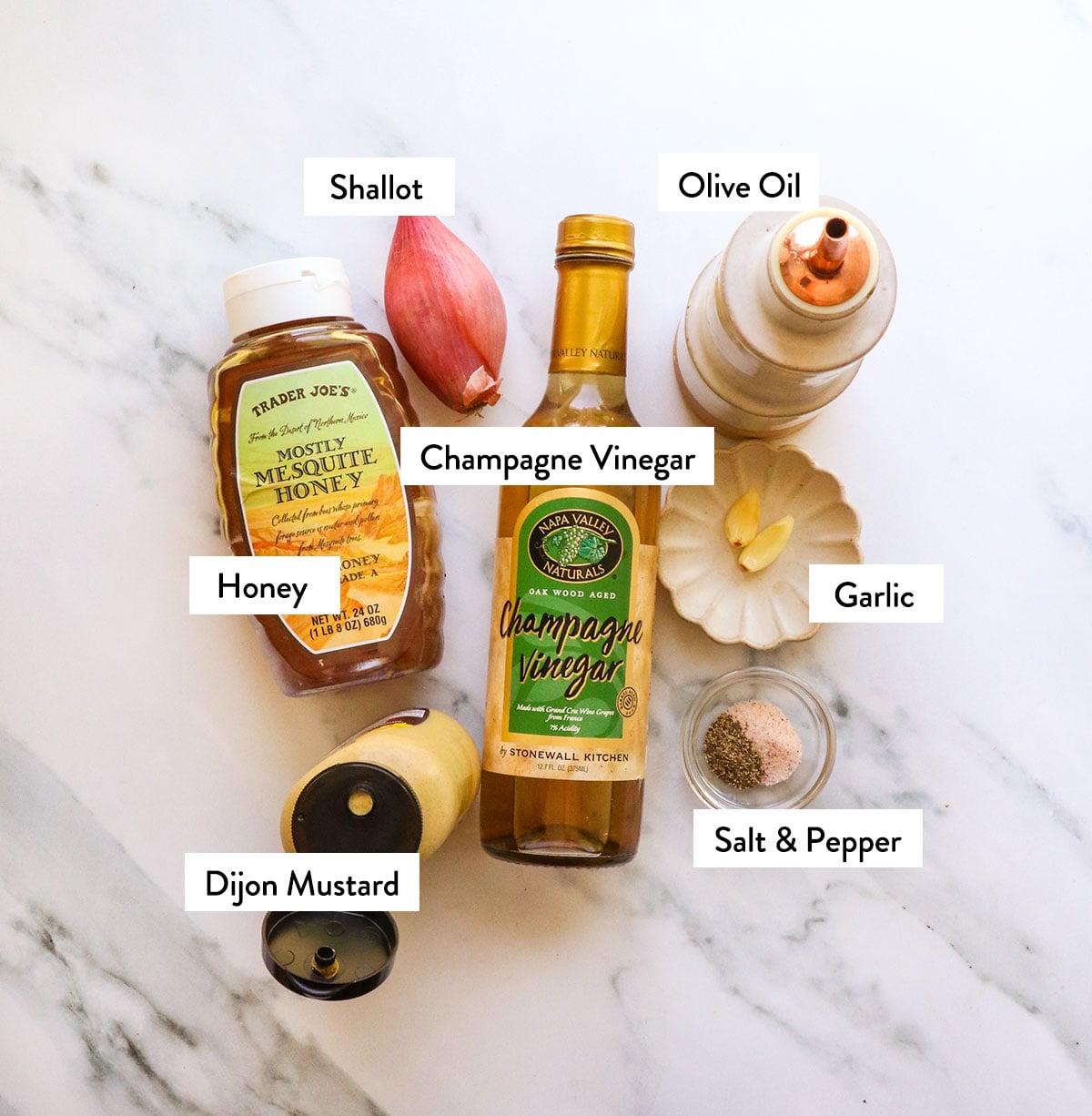 champagne vinegar, honey, shallot, olive oil, and mustard labeled on a marble surface. 