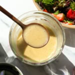 champagne vinaigrette lifted on a spoon over a jar.