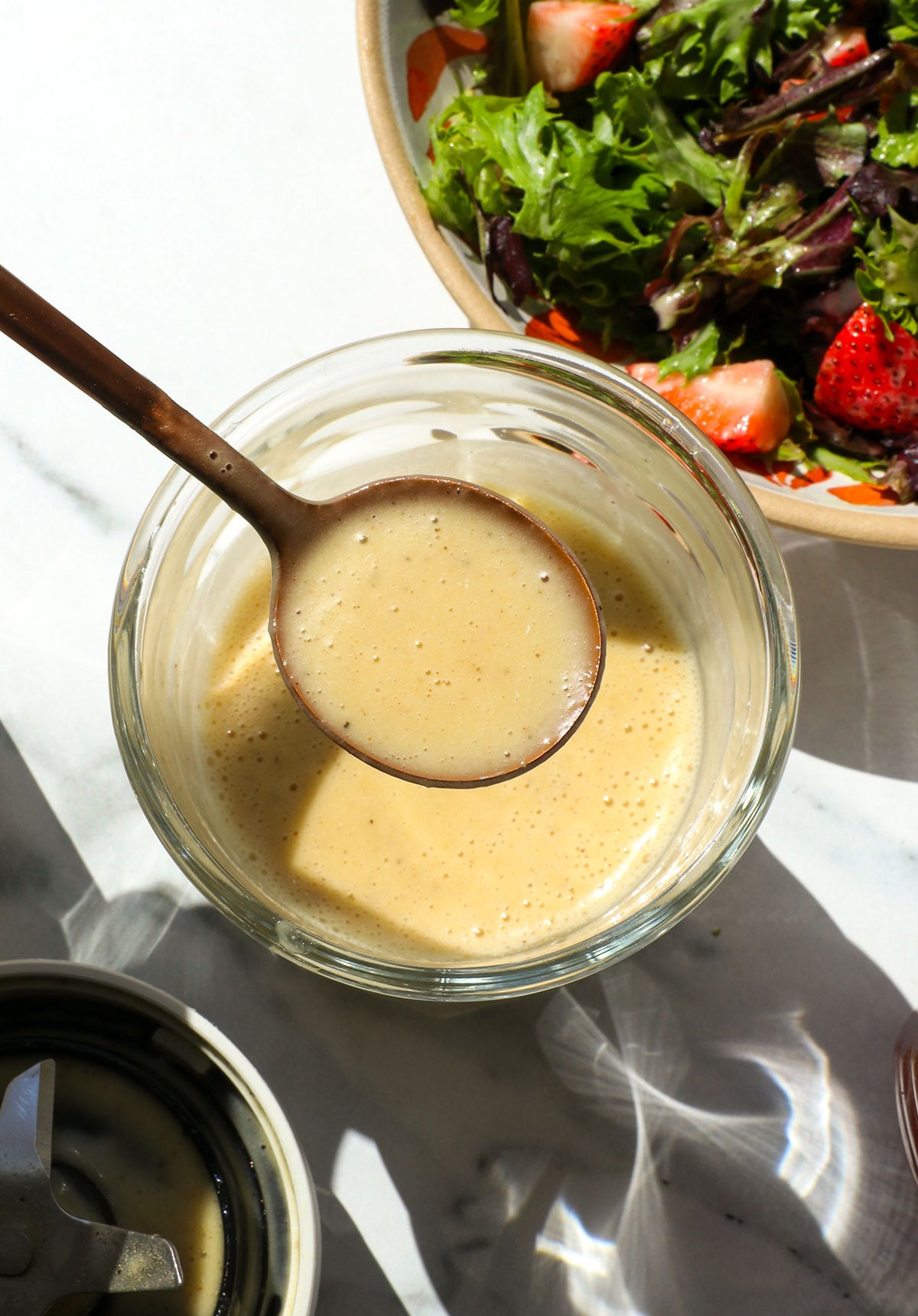 champagne vinaigrette lifted on a spoon over a jar. 