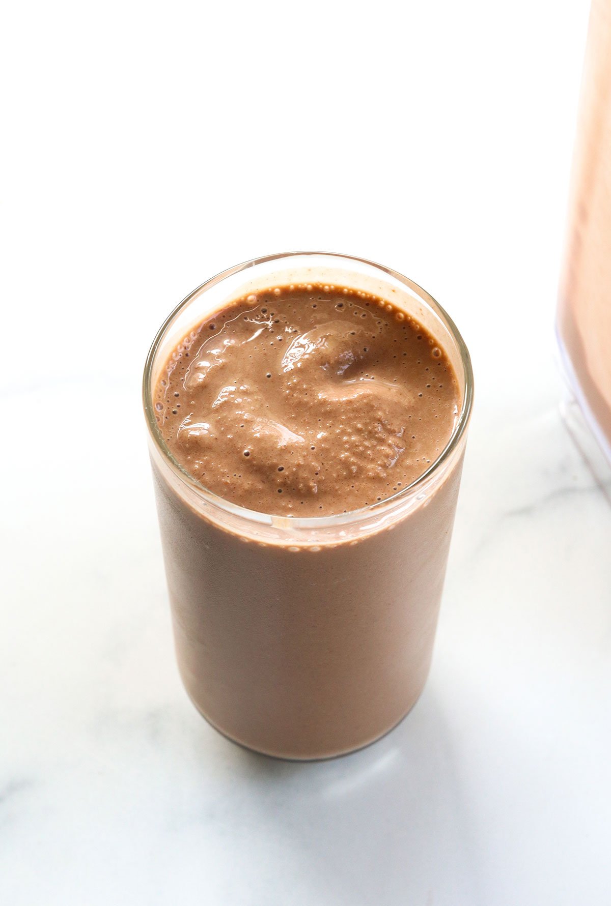 chocolate smoothie in a glass on a white surface.