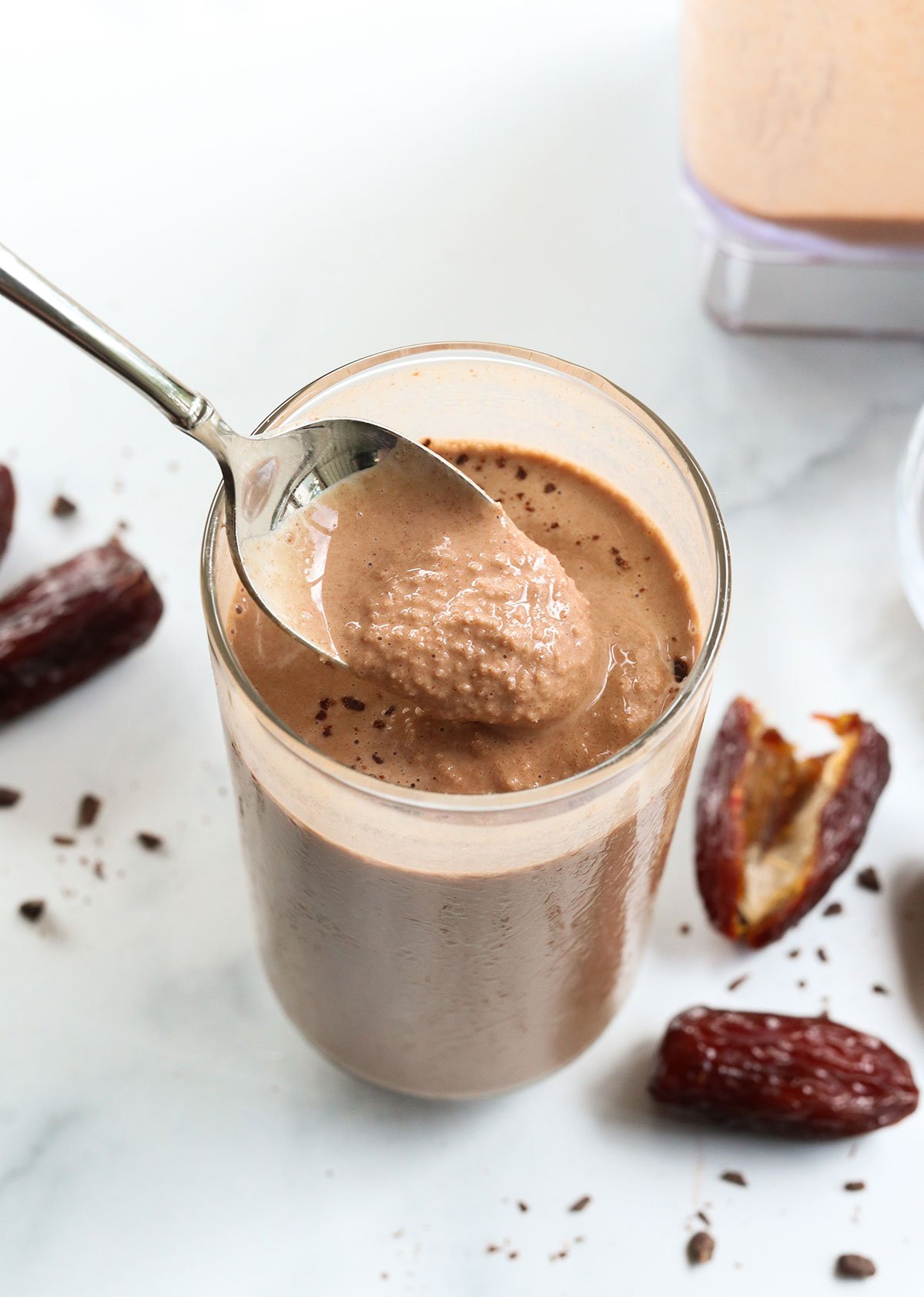 chocolate date smoothie lifted up on a spoon from the glass.