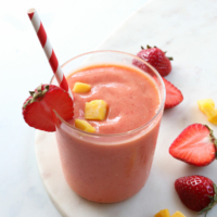 strawberry mango smoothie served with a red and white striped straw.
