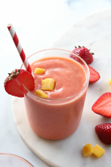 strawberry mango smoothie served with a red and white striped straw.