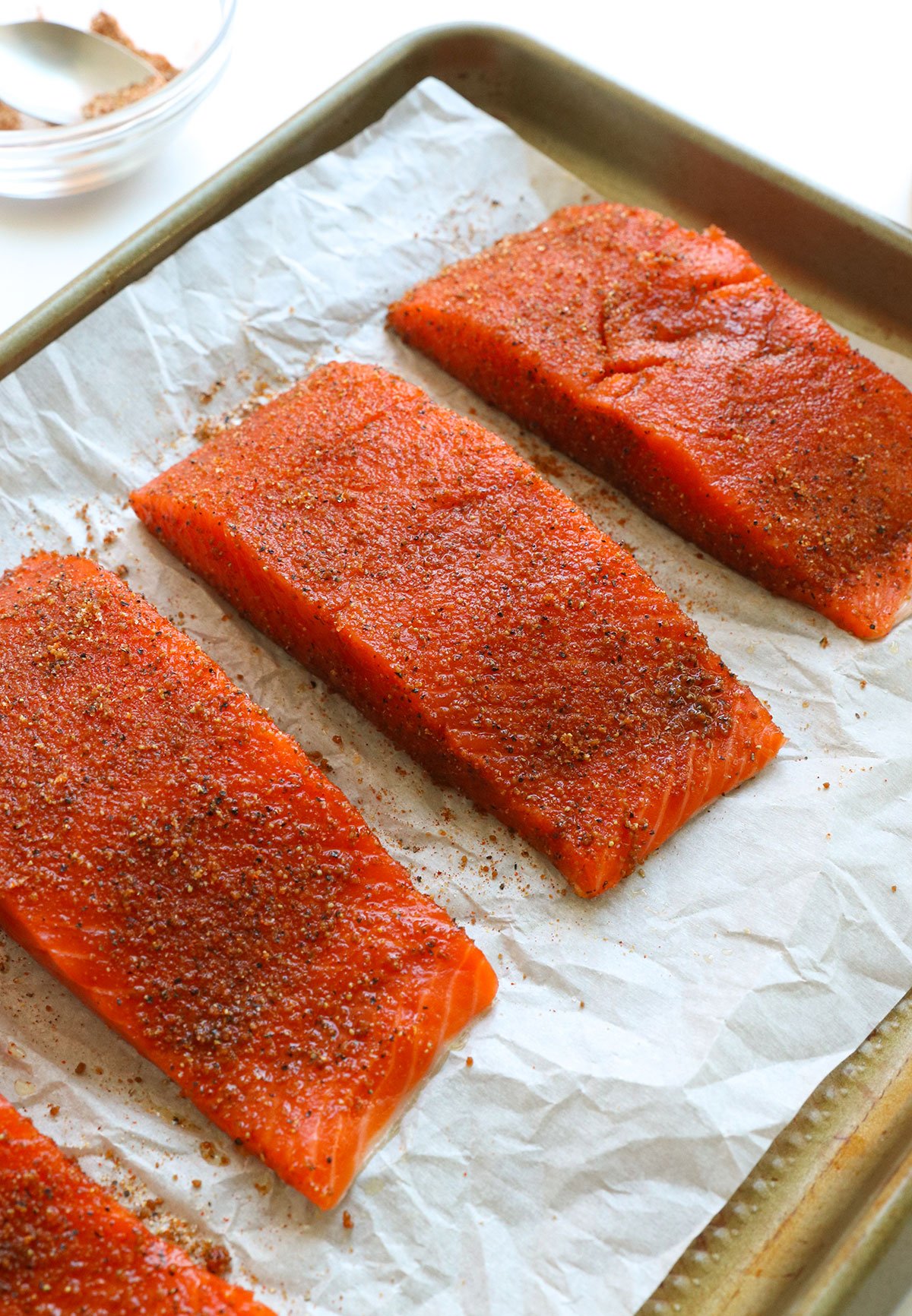 salmon seasoned with the spice rub on a parchment lined pan.