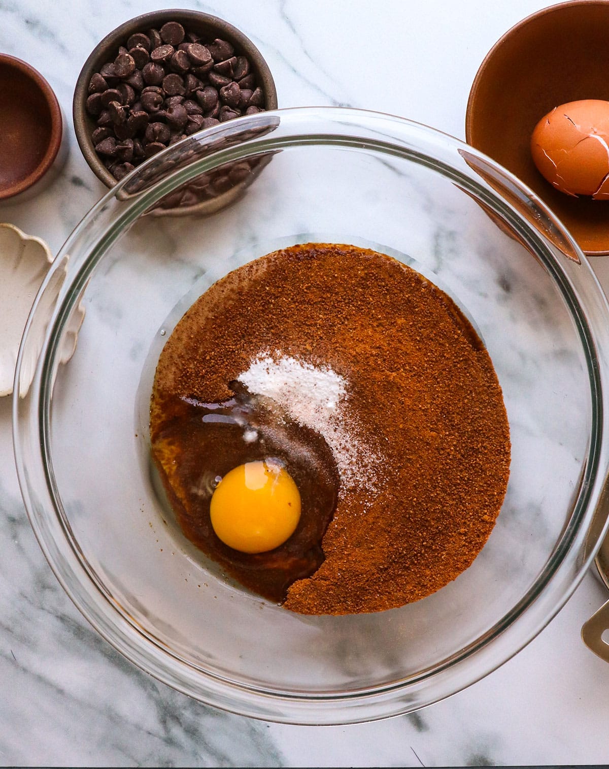 adding almond butter cookie ingredients to a glass bowl.