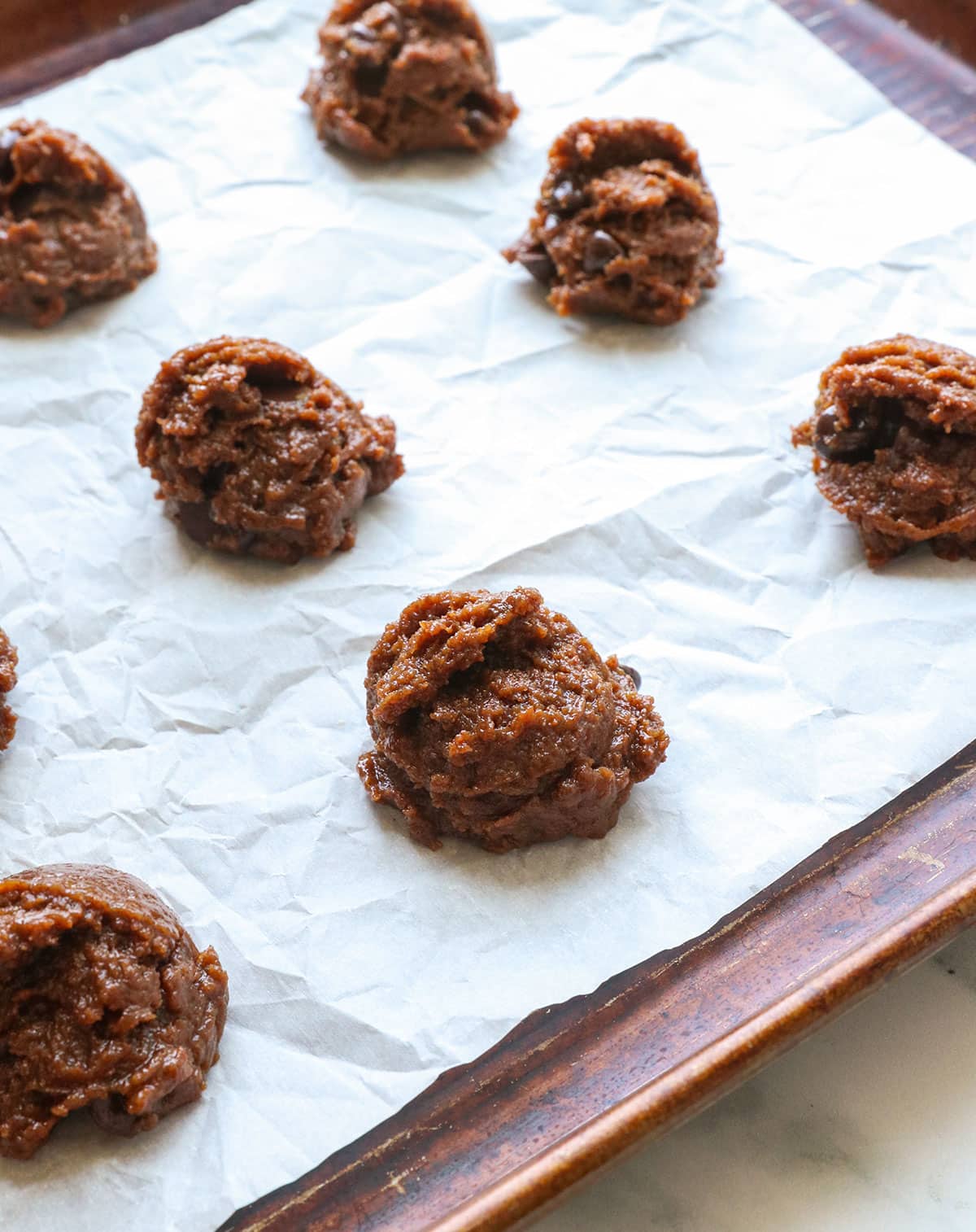 almond butter cookie dough dropped on a lined baking sheet.