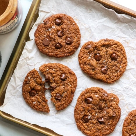 almond butter cookies cooling on a pan with one split in half.