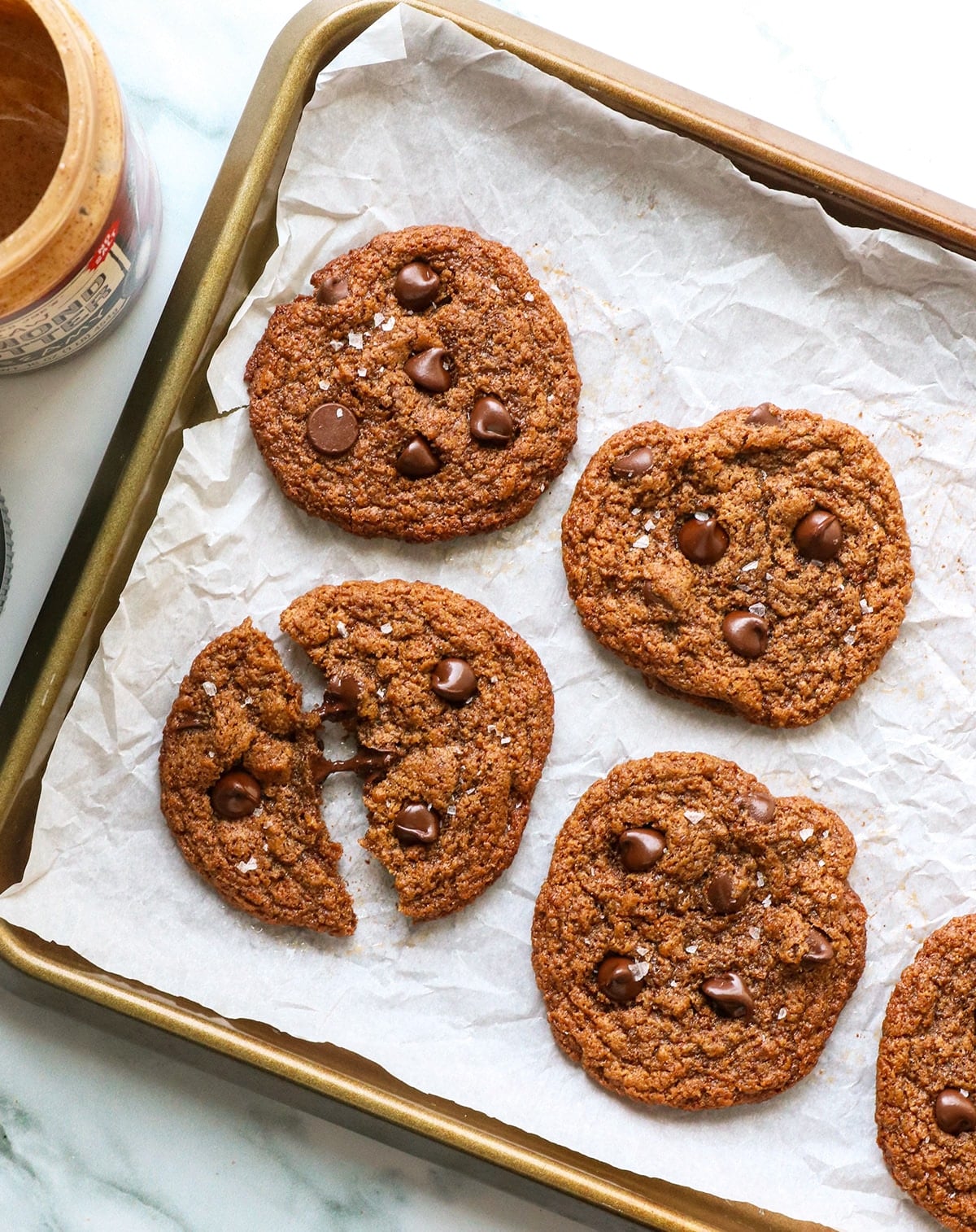 almond butter cookies cooling on a pan with one split in half.