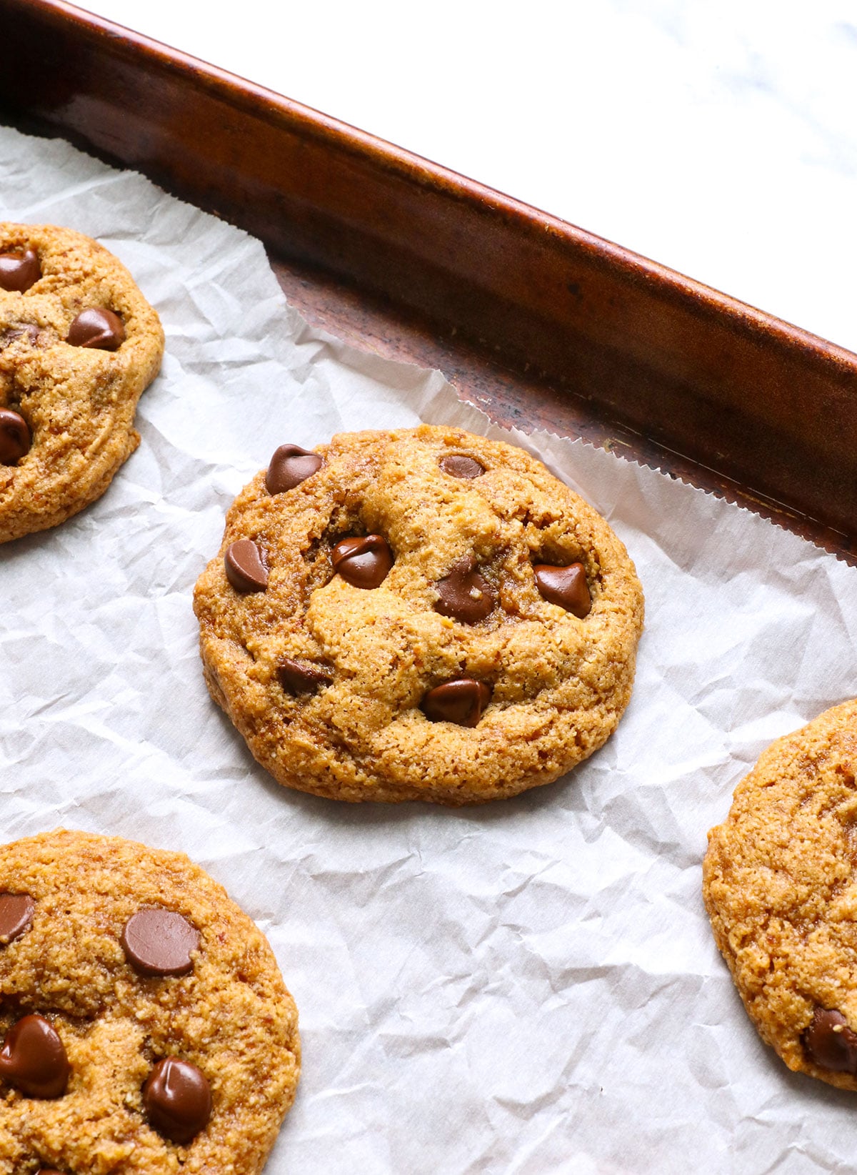 paleo chocolate chip cookie cooling on a lined baking sheet.