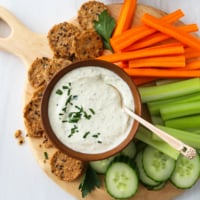 Cottage cheese dip served with sliced veggies and crackers on a platter.