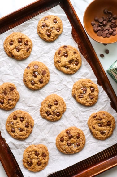 paleo chocolate chip cookies on a parchment paper lined baking sheet overhead.