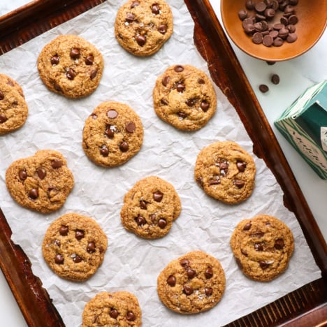paleo chocolate chip cookies on a parchment paper lined baking sheet overhead.