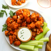 Air fryer buffalo cauliflower served on a plate with celery and dip.