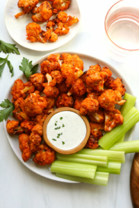 Air fryer buffalo cauliflower served on a plate with celery and dip.