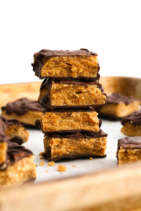 homemade butterfingers stacked on a baking sheet with white background.