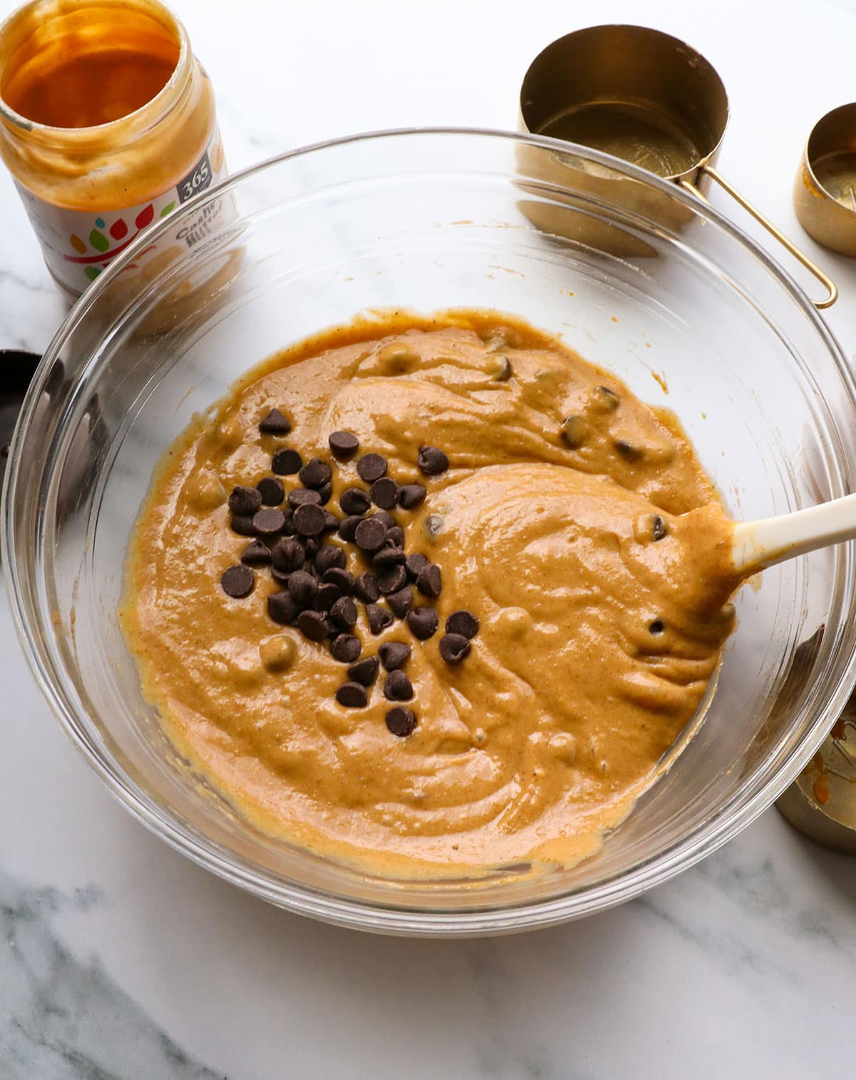 chocolate chips folded into paleo muffin batter in a glass bowl.