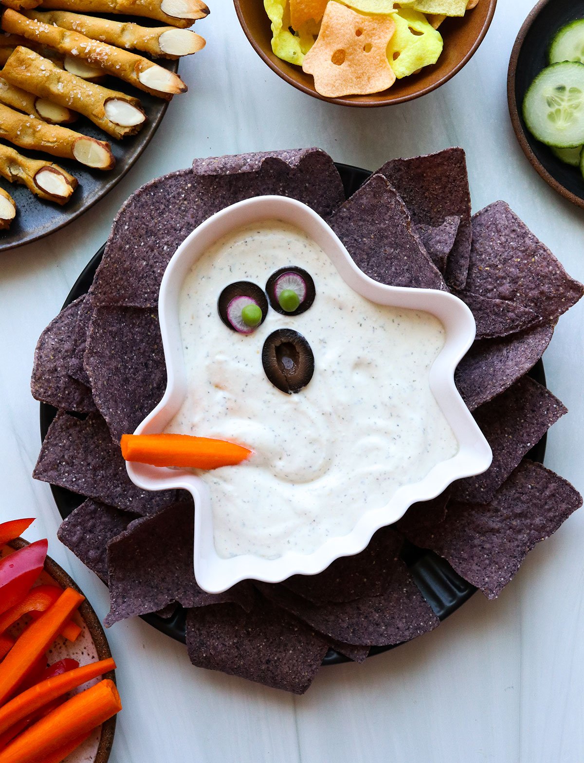 a bowl of ranch dip that looks like a ghost with olive eyes.