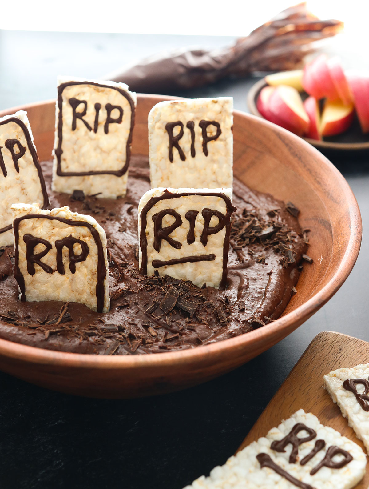 A bowl of chocolate hummus with pretend tombstones made of rice crackers.