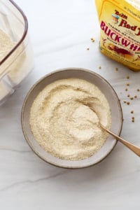 Homemade buckwheat flour in a bowl with a spoon.
