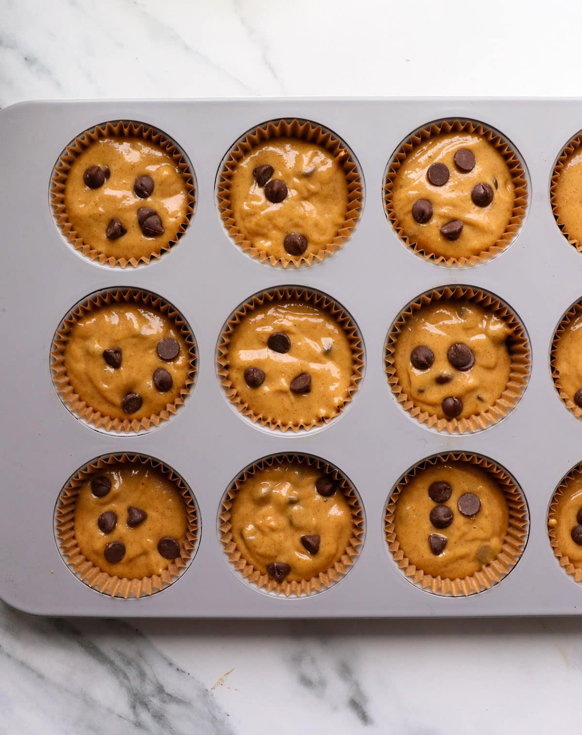 paleo muffin batter in a plan with extra chocolate chips on top.