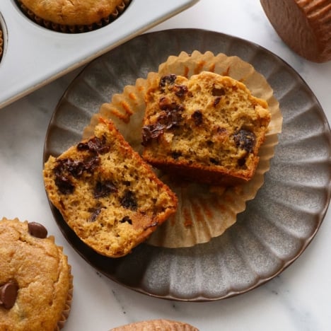 pumpkin paleo muffin split open on a plate to show the fluffy texture.