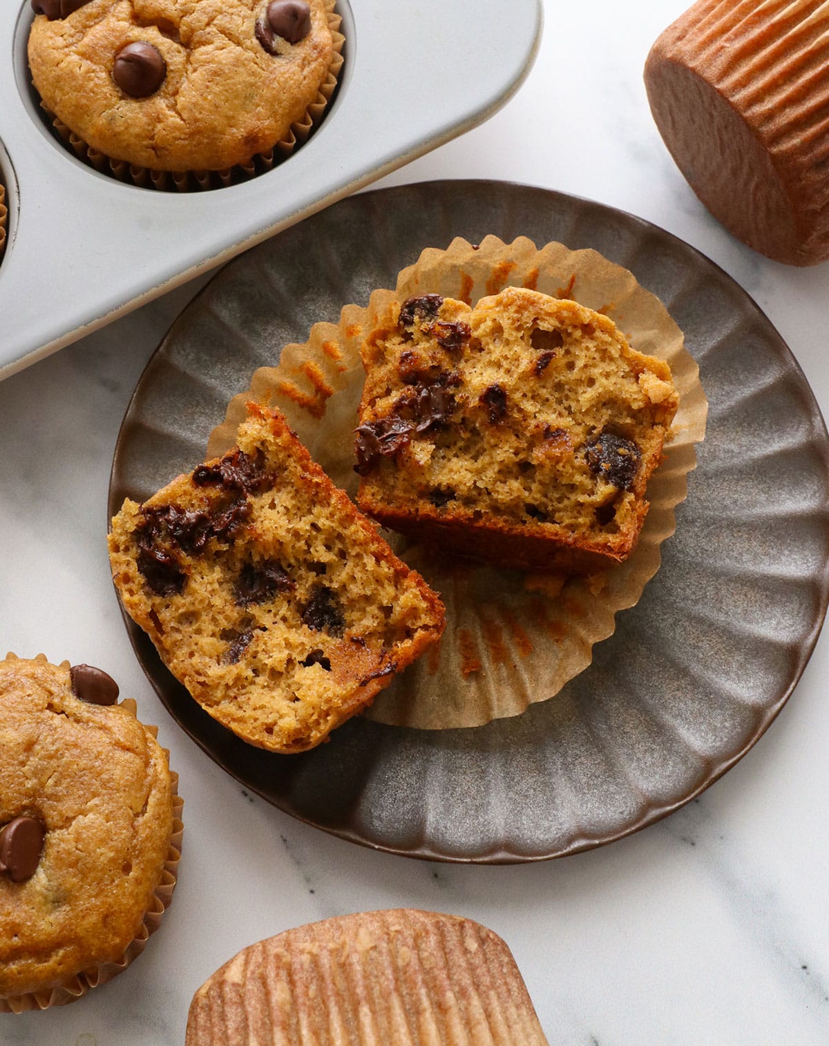 pumpkin paleo muffin split open on a plate to show the fluffy texture.
