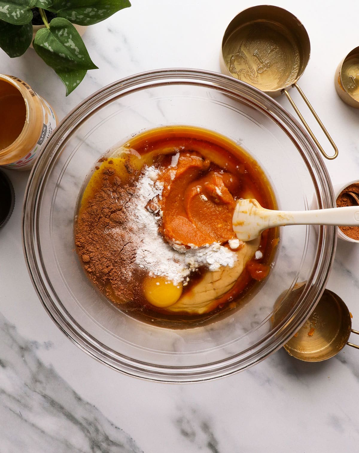 pumpkin puree, eggs, nut butter, and spices added to a glass bowl.