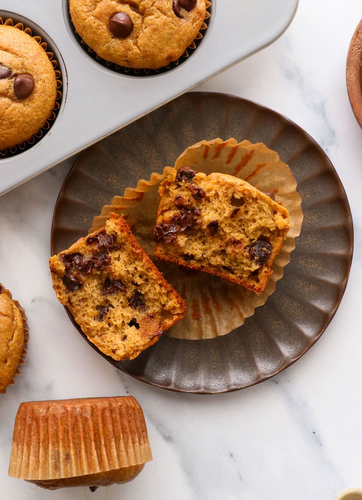 paleo pumpkin muffin with chocolate chips split in half on a plate.