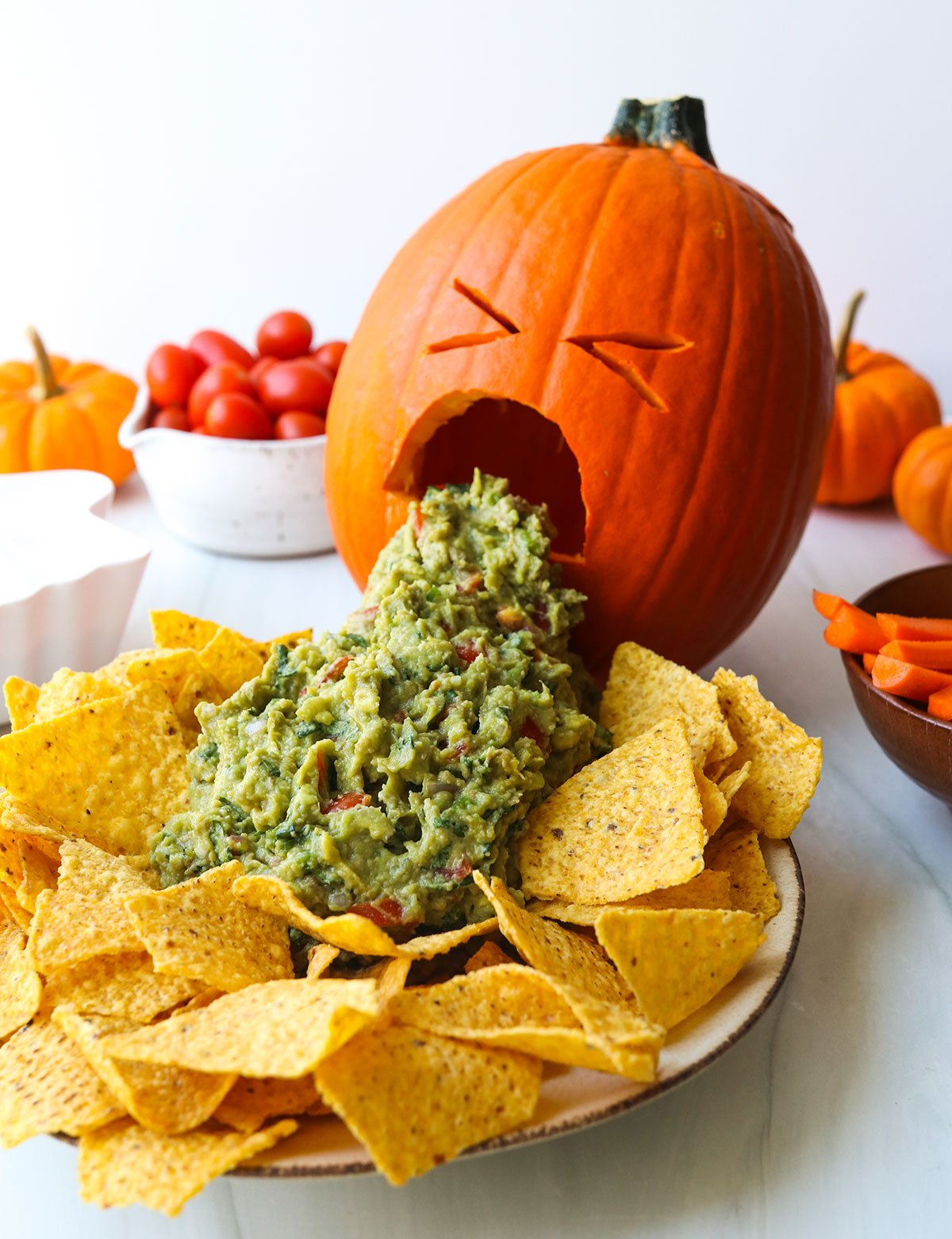 A carved pumpkin that looks like it's puking guacamole onto a plate.