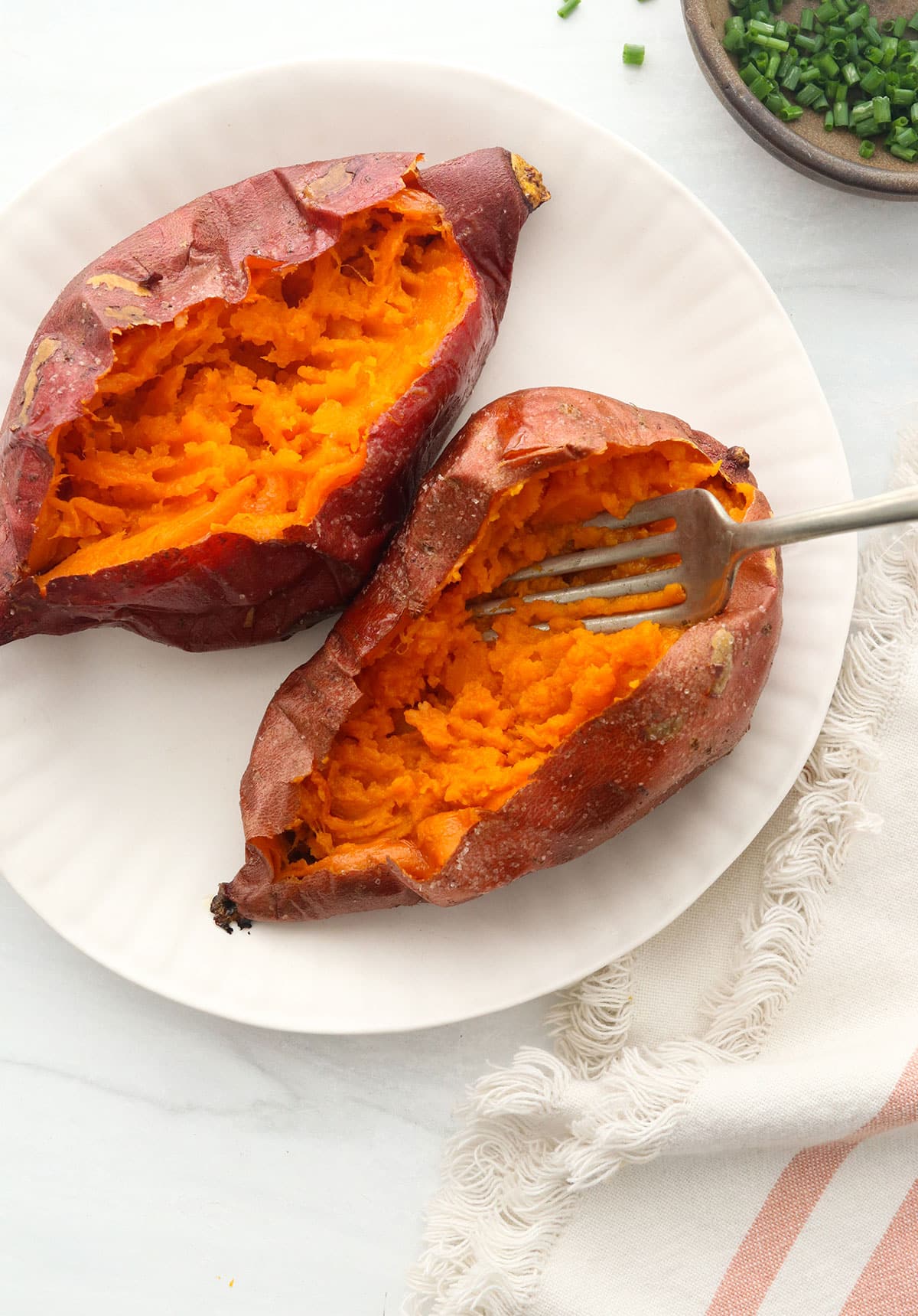 sweet potatoes split in half to show the insides with a fork.