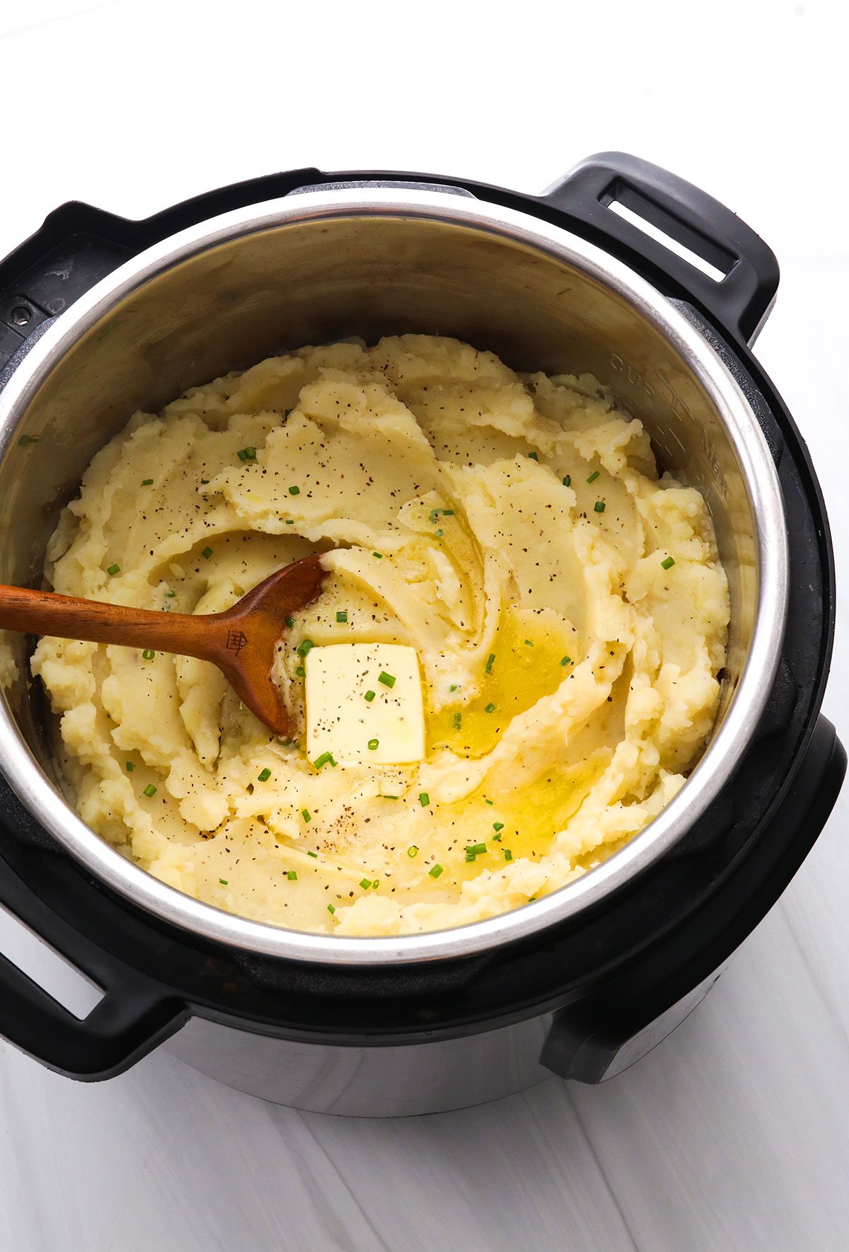 Mashed Potatoes topped with butter and chives in the Instant Pot.