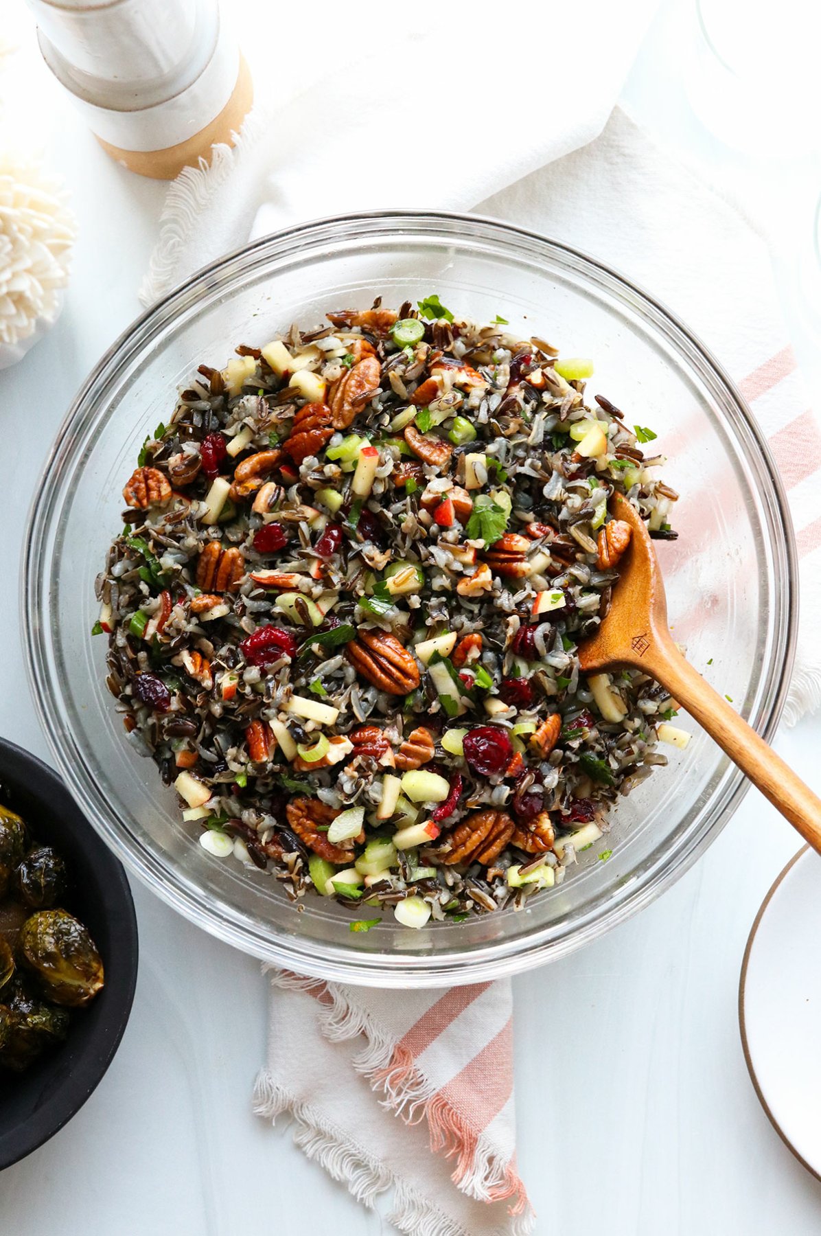 Wild rice salad overhead in a glass bowl on a striped towel.