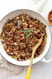 Wild rice stuffing in a large white skillet with serving spoon.