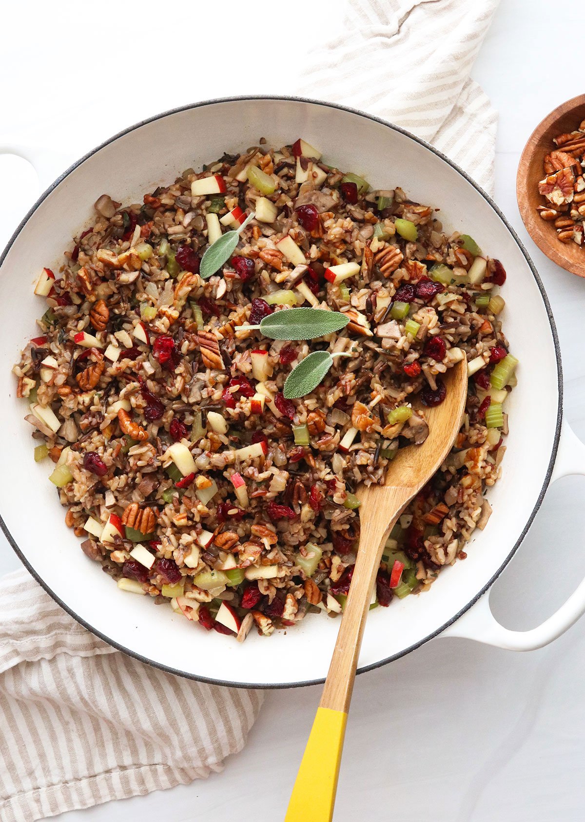 Wild rice stuffing in a large white skillet with serving spoon.