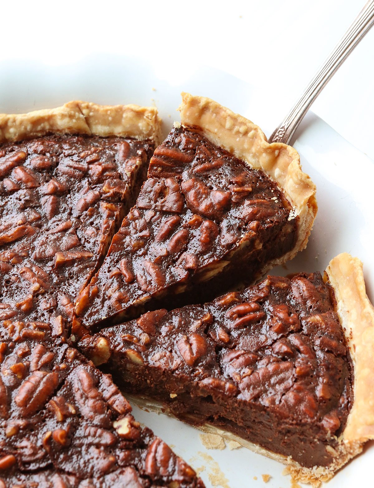 Chocolate pecan pie slice lifted up from a pie pan.