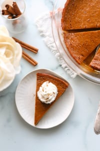 Crustless pumpkin pie sliced and topped with whipped cream.