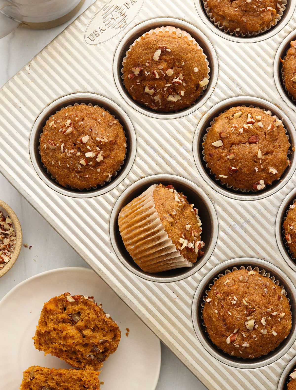 sweet potato muffins in a pan with one split in half nearby.